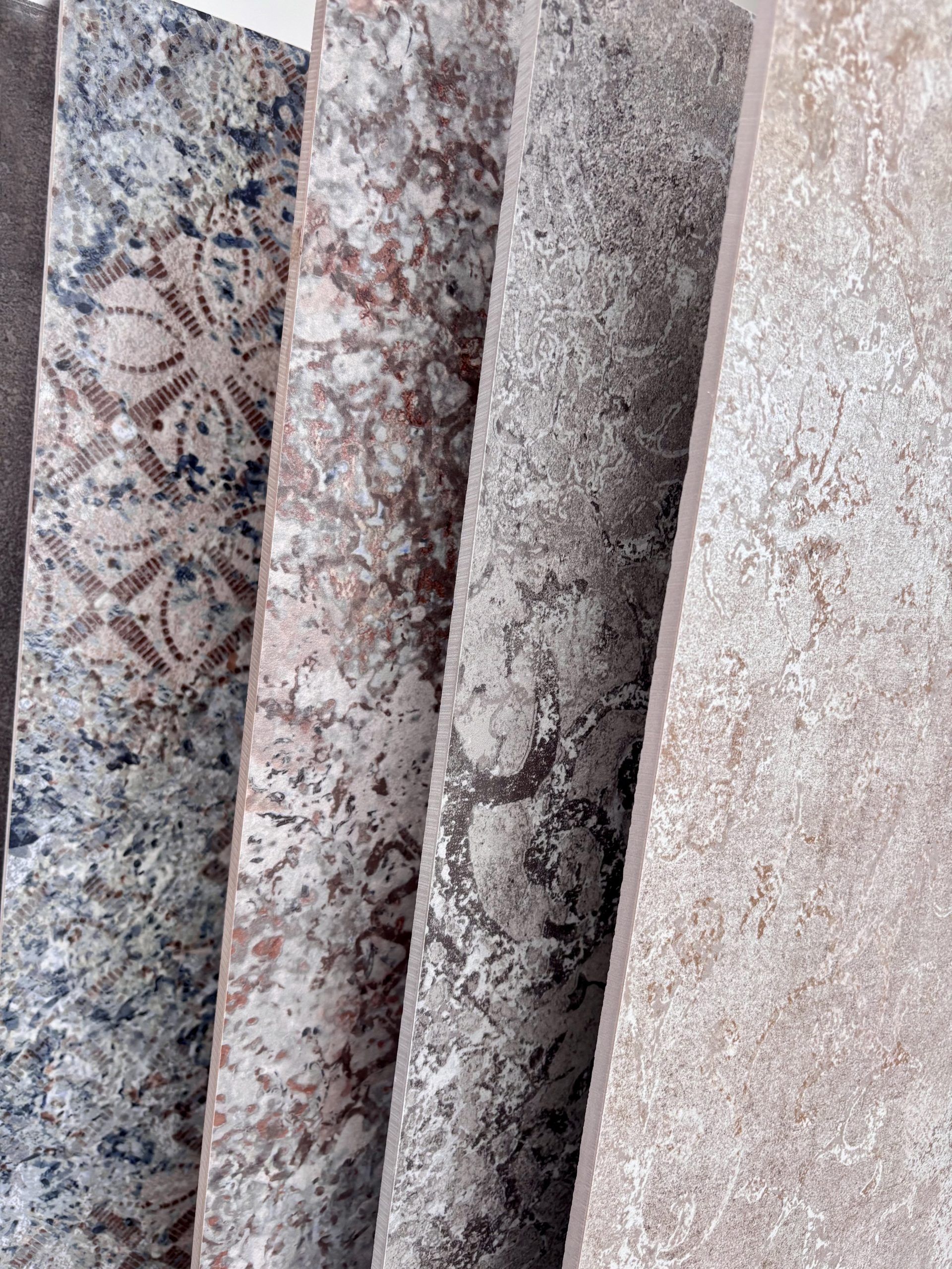 Nahaufnahme von großformatigen Fliesenmustern in einem Fliesenausstellungsständer, im Vordergrund eine glänzend weiße und eine rote Fliese.