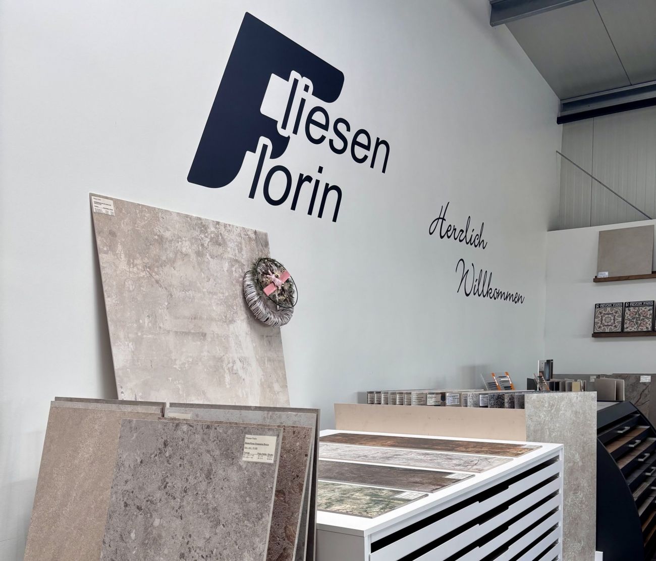 Mehrere dekorative Fliesenmuster in Grau und Weiß mit grafischen und geometrischen Designs in einem Präsentationsständer.