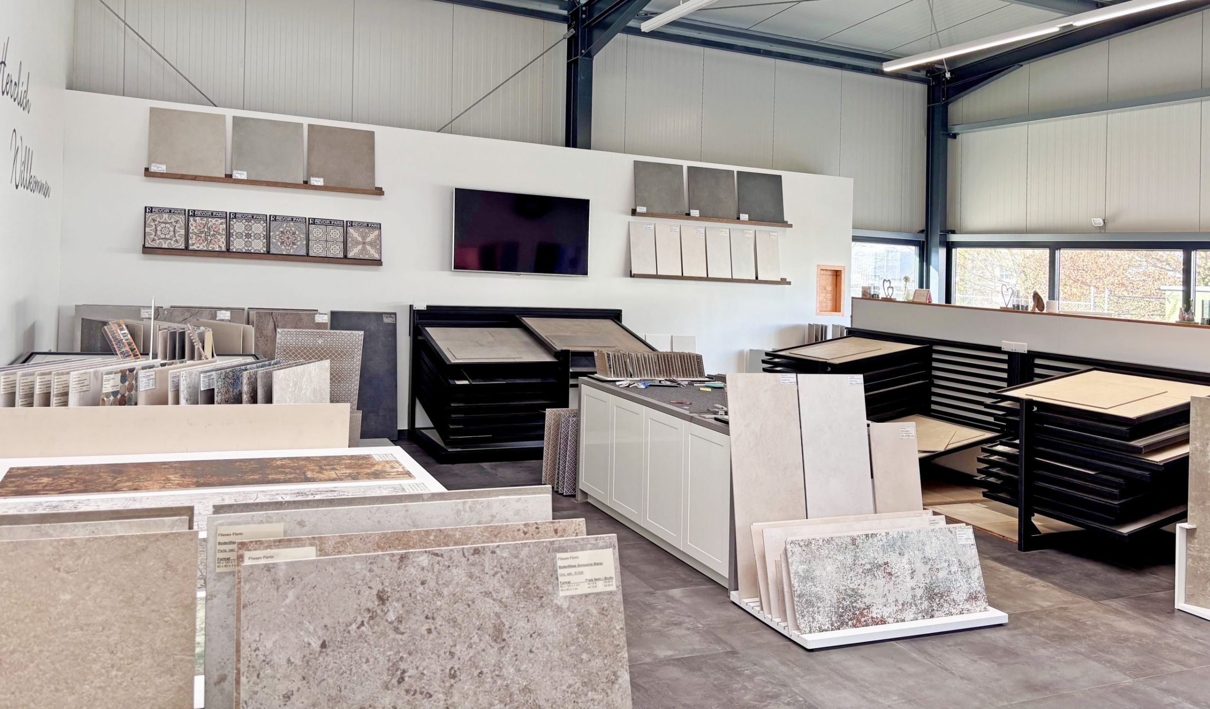 Nahaufnahme von großformatigen Fliesenmustern in einem Fliesenausstellungsständer, im Vordergrund eine glänzend weiße und eine rote Fliese.