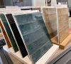 Nahaufnahme von großformatigen Fliesenmustern in einem Fliesenausstellungsständer, im Vordergrund eine glänzend weiße und eine rote Fliese.