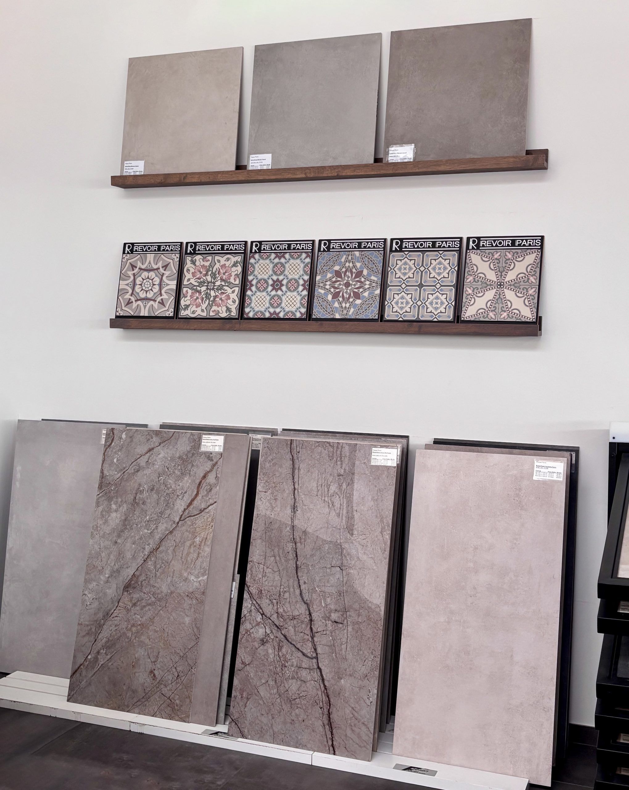 Nahaufnahme von großformatigen Fliesenmustern in einem Fliesenausstellungsständer, im Vordergrund eine glänzend weiße und eine rote Fliese.