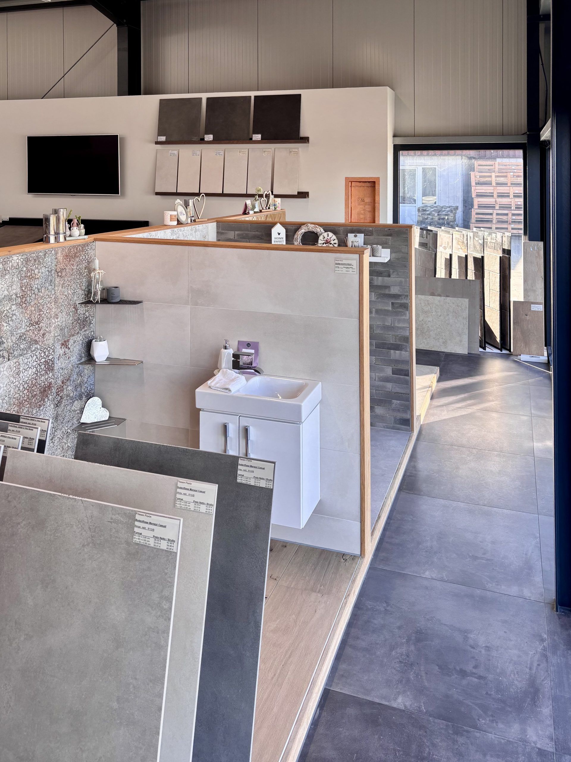 Nahaufnahme von großformatigen Fliesenmustern in einem Fliesenausstellungsständer, im Vordergrund eine glänzend weiße und eine rote Fliese.