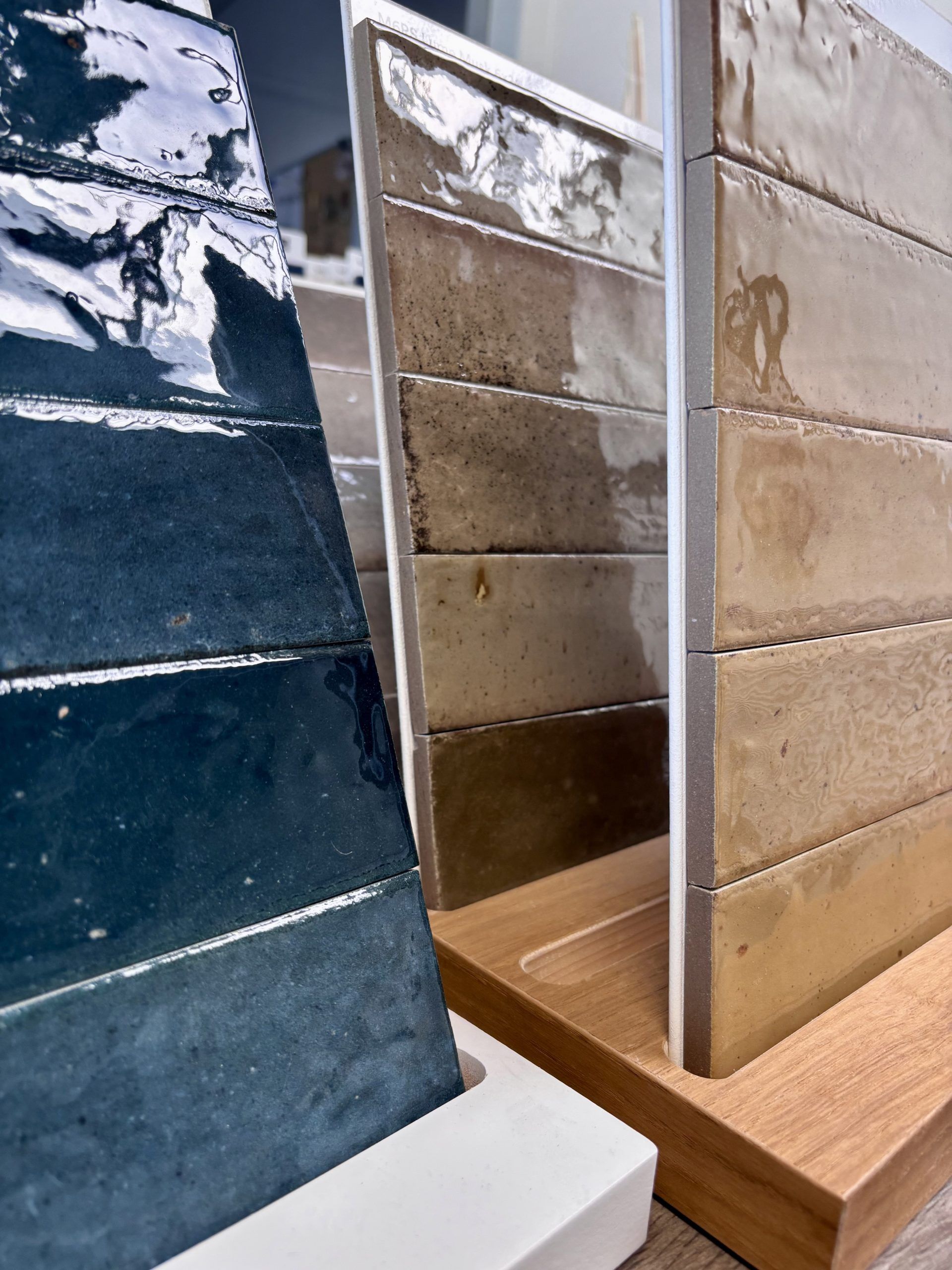 Nahaufnahme von großformatigen Fliesenmustern in einem Fliesenausstellungsständer, im Vordergrund eine glänzend weiße und eine rote Fliese.